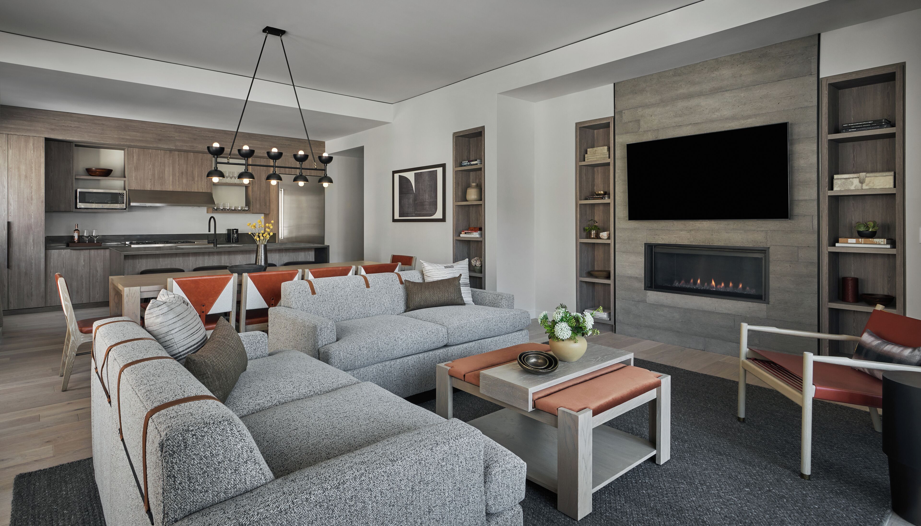 A modern living room with a sectional sofa, a fireplace, and a kitchen in the background.