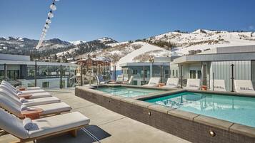 Una piscina al aire libre, sombrillas, sillones reclinables de piscina