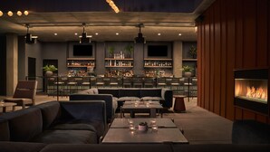A modern bar area with sofas, tables, and a fireplace. - Pendry Park City (Park City)