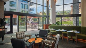 A modern interior with large windows, a green sofa, and a piano. - Pendry Park City (Park City)