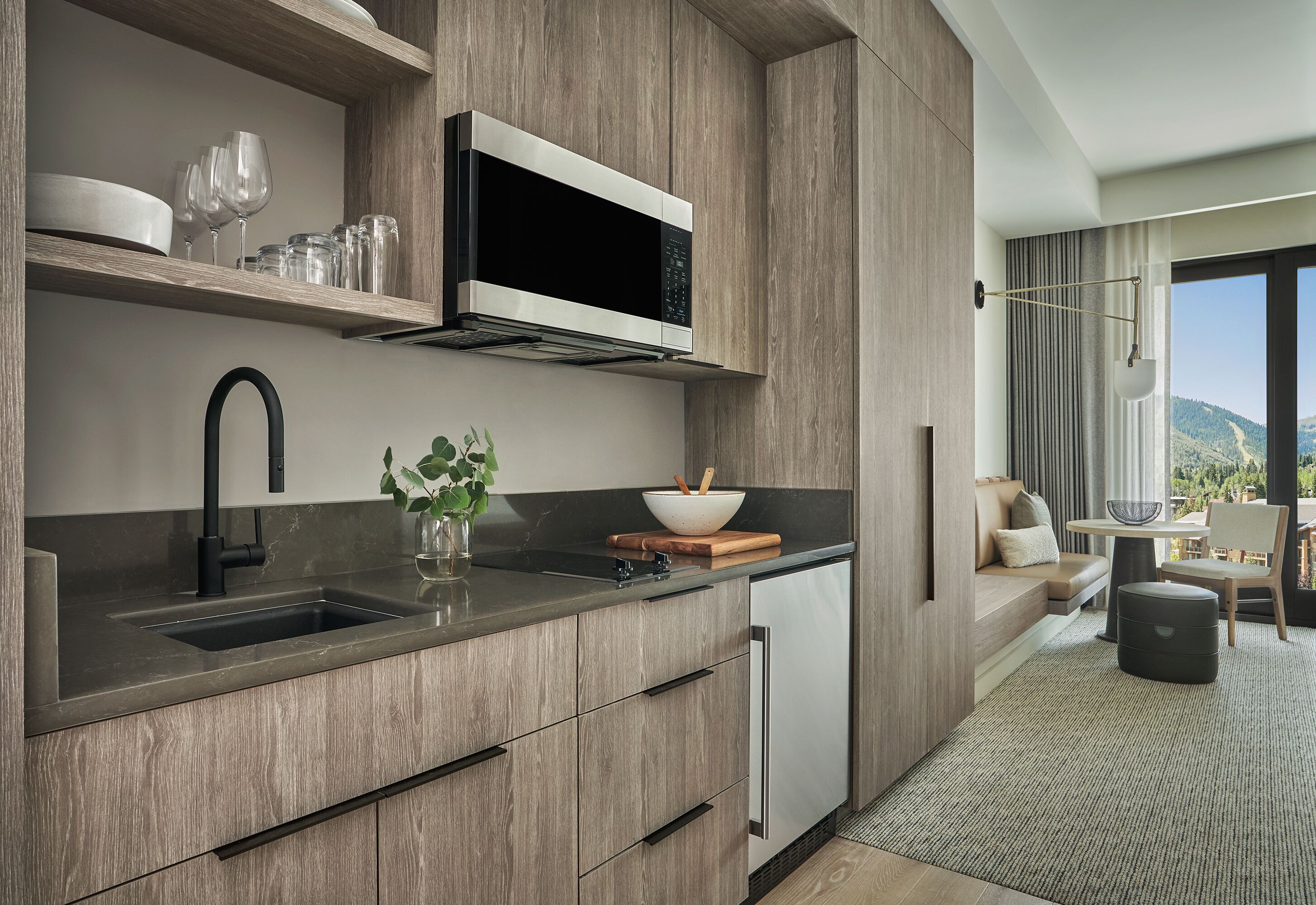 A modern kitchen with a built-in microwave, a sink, and a dining area with a view of the outdoors.