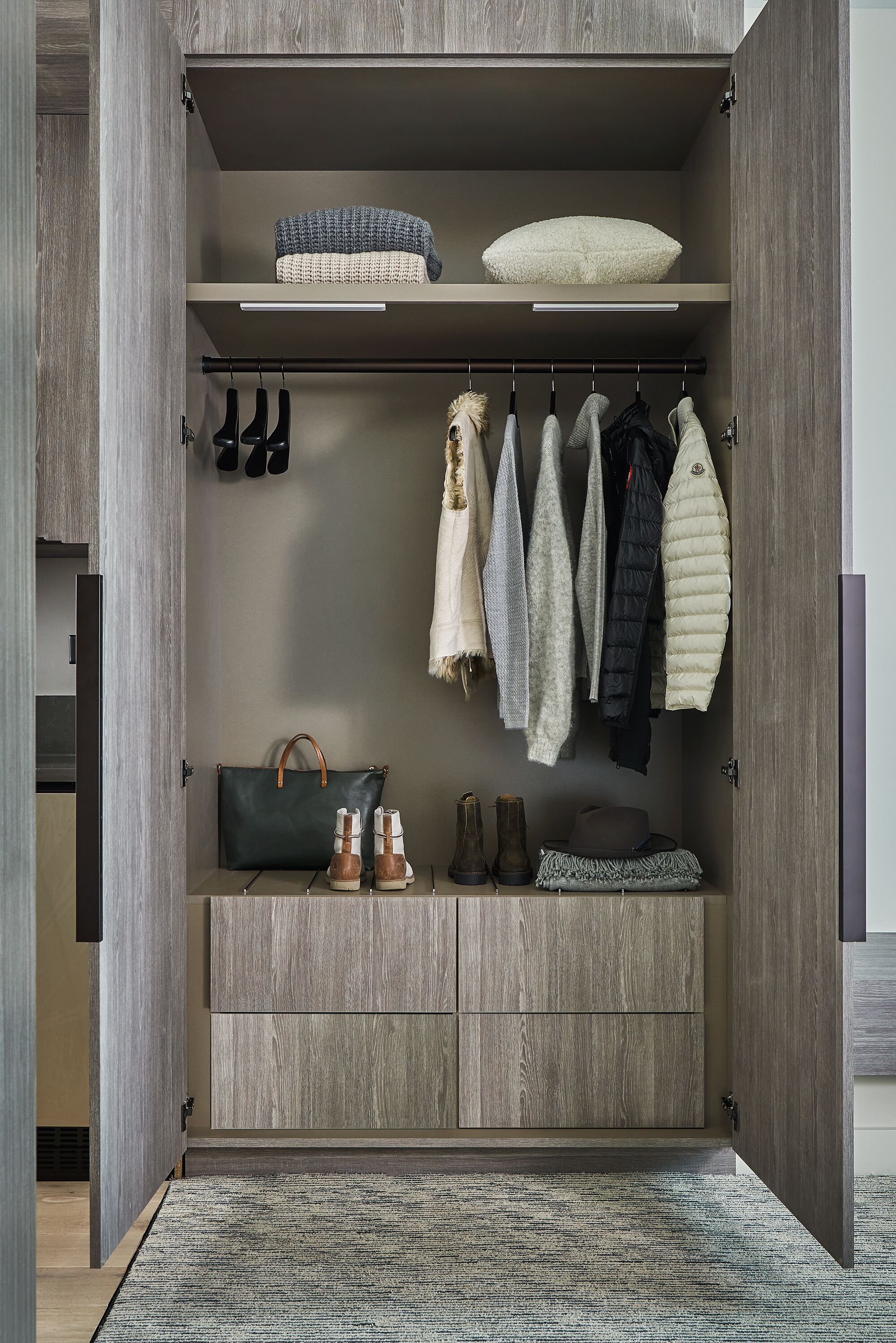 A walk-in closet with wooden shelves, hanging space, and drawers.