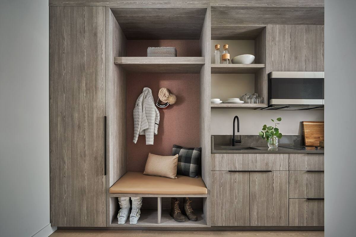Une cuisine compacte avec des meubles en bois, un banc avec espace de rangement, un évier et un four à micro-ondes.