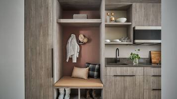 A compact kitchen with wooden cabinetry, a bench with storage, a sink, and a microwave.