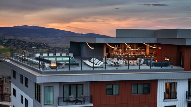A rooftop bar with lounge chairs, a pool, and a bar area. - Pendry Park City (Park City)