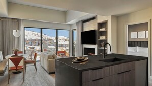 A modern kitchen with a large island, a dining area with a view of the mountains, and a cozy seating area with a fireplace. - Pendry Park City (Park City)