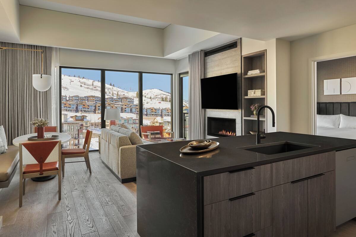 Une cuisine moderne dotée d’un grand îlot central, d’un coin repas offrant une vue sur les montagnes et d’un espace salon confortable avec une cheminée.