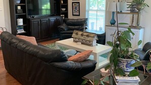 A living room with a black leather sofa, a coffee table, and a bookshelf.