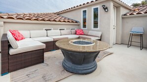 A patio with a sectional sofa, a round table, and a small chair.