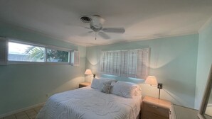 A bedroom with a bed, two bedside tables, a ceiling fan, a window, and a radiator. - Oceanfront Beach Cottage with Private beach access in beautiful Juno Beach. (Juno Beach)