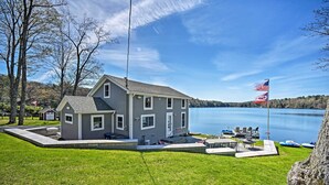 A two-story house with a dock and a flagpole, overlooking a lake. - BBQ Ready: Lakeside Milford Home w/ Paddleboat (Milford)