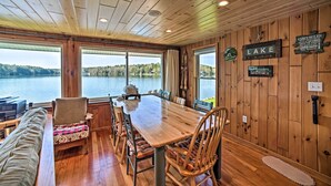 A wooden cabin with a large dining table, chairs, and a bench. There are windows overlooking a lake. - BBQ Ready: Lakeside Milford Home w/ Paddleboat (Milford)