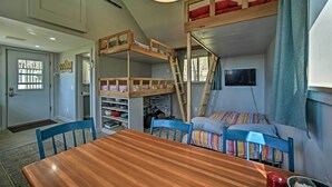 A compact room with bunk beds, a wooden table, and a TV. - Fire Pit + Gas Grill: Secluded Studio in Milford! (Milford)
