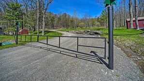 A gravel path leading to a wooden cabin with a metal gate and a green directional sign. - Fire Pit + Gas Grill: Secluded Studio in Milford! (Milford)