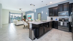 A modern kitchen with dark cabinets, stainless steel appliances, and a large island. - DG1193 Champions Gate Condo 2Bedrooms 2Bathrooms Free Waterpark (Kissimmee)