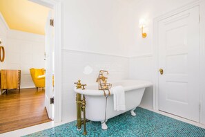 A bathroom with a freestanding bathtub, a white door, and a yellow chair in the adjacent room. - Historic and Opulent Pacific Heights Mansion Overlooking Alta Plaza Park (Le Monetier les Bains)