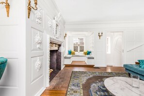 A spacious living room with a fireplace, a seating area with cushions, and a large window. - Historic and Opulent Pacific Heights Mansion Overlooking Alta Plaza Park (Le Monetier les Bains)