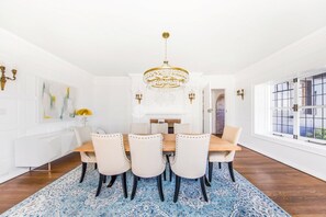 A dining room with a wooden table, white chairs, a blue patterned rug, and a chandelier. - Historic and Opulent Pacific Heights Mansion Overlooking Alta Plaza Park (Le Monetier les Bains)