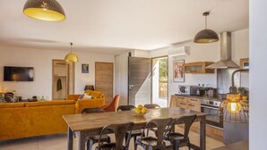 Ett modernt kök med matplats, en soffa och en tv.