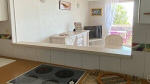 A kitchen with a stove, cabinets, and a window overlooking a dining area.