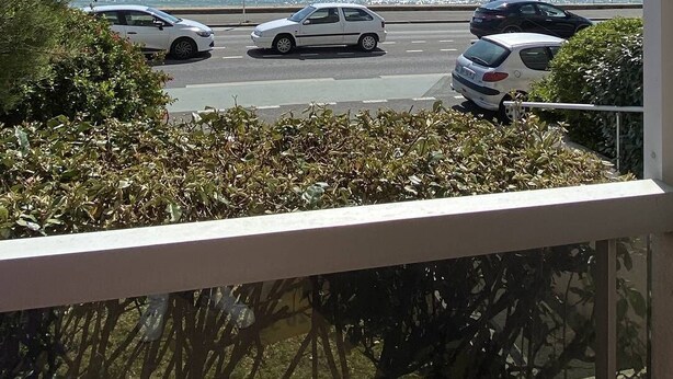 A coastal road with parked cars and a clear view of the sea.