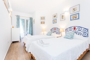A hotel room with two beds, a white wardrobe, a window with curtains, and wall art. - CoolHouses Algarve Luz | Villa 76 LBC (Luz)