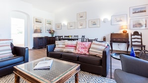Una sala de estar con un sofá, sillones, una mesa de centro y un comedor con sillas y una mesa.