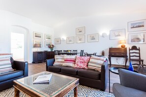 A living room with a sofa, armchairs, a coffee table, and a dining area with chairs and a table.