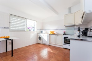 A compact kitchen with a washing machine, a microwave, and a stove.