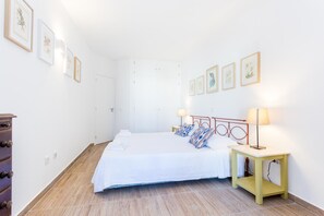 A hotel room with a bed, bedside lamps, a dresser, and framed artwork on the walls.