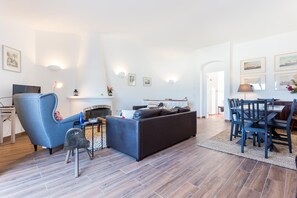 Una sala moderna con chimenea, un comedor con mesa y sillas, y un televisor sobre un mueble.