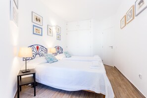 Una habitación de hotel con dos camas, una mesita de noche y un armario.