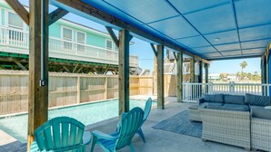 Un espacio al aire libre cubierto con piscina, dos sillas Adirondack y un sofá de mimbre.