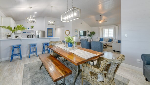 Una cocina amplia con una mesa de comedor de madera, taburetes altos azules y una lámpara colgante.