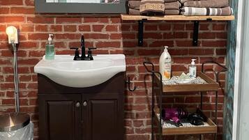 A bathroom with a white sink, dark wooden cabinets, a mirror, and a shelf with folded towels.