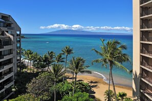 Un hôtel situé en bord de mer, offrant une vue sur l’océan et sur une montagne qui se dessine à l’horizon.