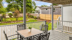 A covered patio with a wooden table and chairs, surrounded by a white railing.