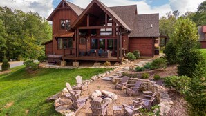 A two-story wooden house with a porch, outdoor seating area, and a stone fire pit. - Happy Trails - Pet friendly Eagles Nest with view, hot tub, fire pit (Banner Elk)