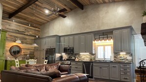 A spacious kitchen with grey cabinets, a stainless steel refrigerator, and a central island. - Elegant Country Cottage (Crawford)