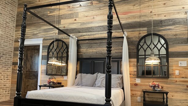 A four-poster bed with a canopy, a wooden ceiling, and a brick wall. - Elegant Country Cottage (Crawford)
