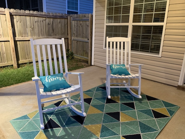 Relax in style with two plush rocking chairs on a geometric-patterned rug, perfect for unwinding in an outdoor space.