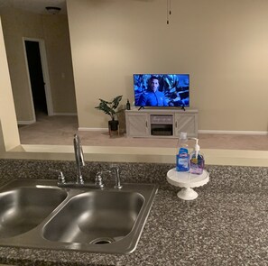 Enjoy cooking in this well-equipped kitchen with a stainless steel sink, granite countertop, and mounted TV.