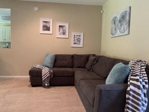 Cozy living space with a sectional sofa, throw pillows, and framed artworks.