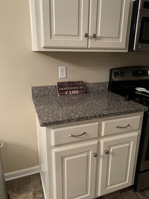 Kitchen area with white cabinetry, granite countertop, and modern appliances.
