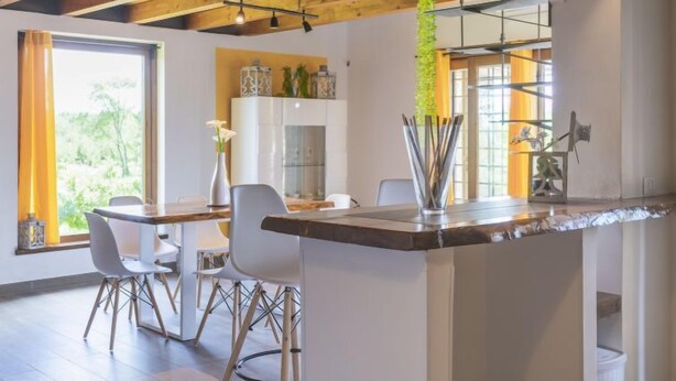 A modern kitchen with a central island, white cabinetry, and a hanging plant. - Melograno by Interhome (Lago di Vico)
