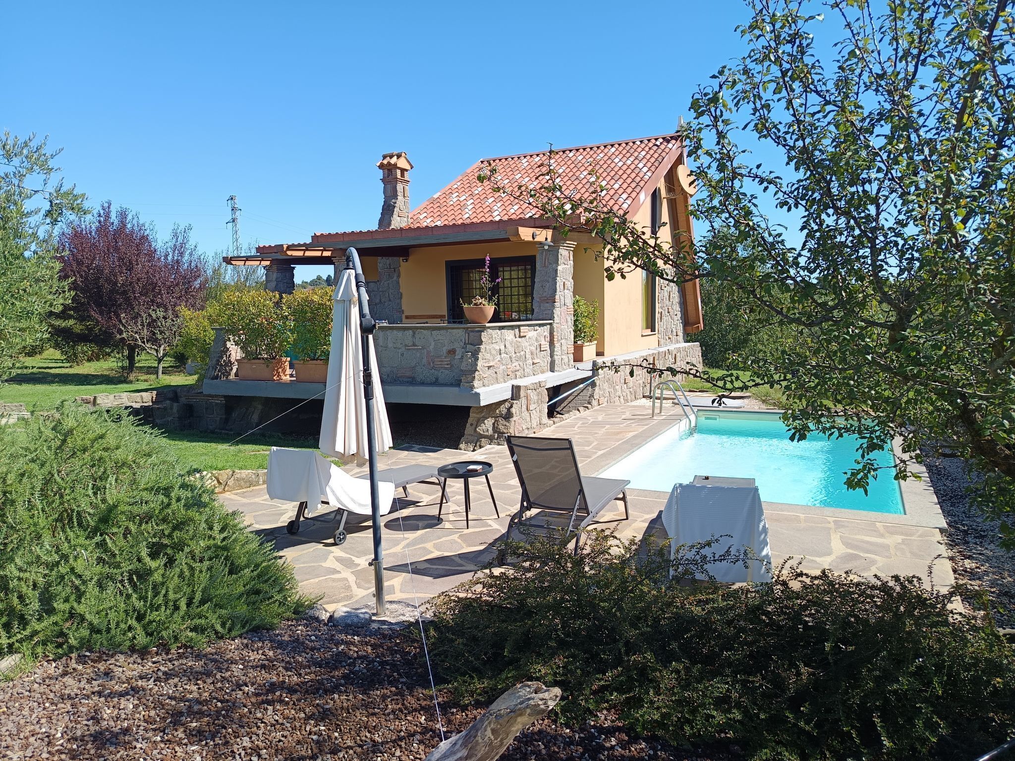 A house with a stone exterior, a swimming pool, and outdoor seating.