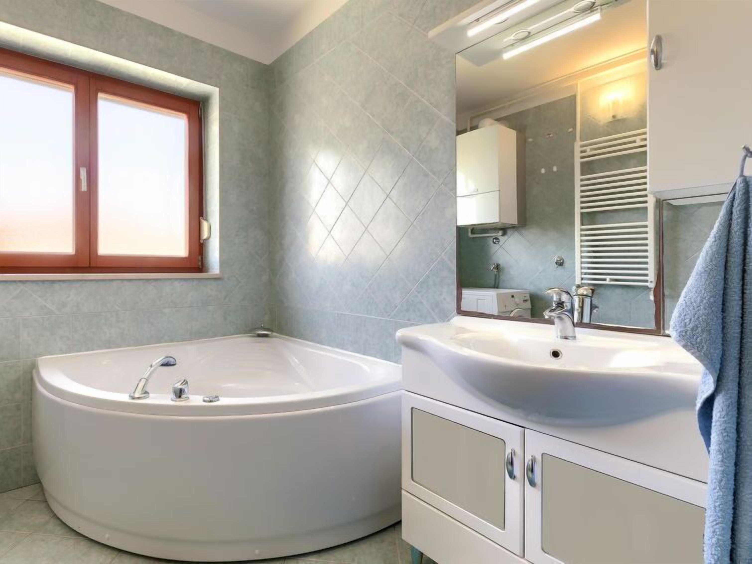 A bathroom with a freestanding bathtub, a sink, and a mirror.