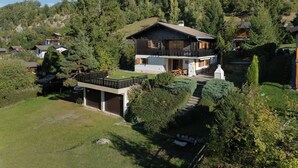 A two-story house with a balcony, surrounded by a forested hillside. - Wonderful private villa for 8 people with WIFI, terrace, pets allowed and panoramic view (La Tzoumaz)