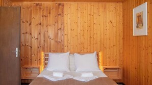 A wooden-paneled room with a bed, two bedside tables, and a door. - Wonderful private villa for 8 people with WIFI, terrace, pets allowed and panoramic view (La Tzoumaz)