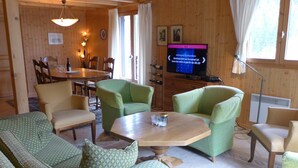 Una sala de estar acogedora con un sofá, sillas, una mesa de centro y una televisión.